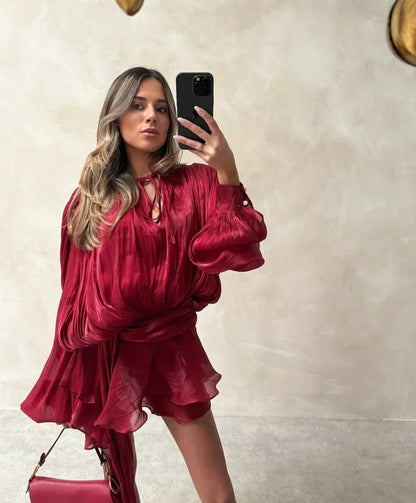 Woman taking a mirror selfie wearing a red outfit with a pink handbag.