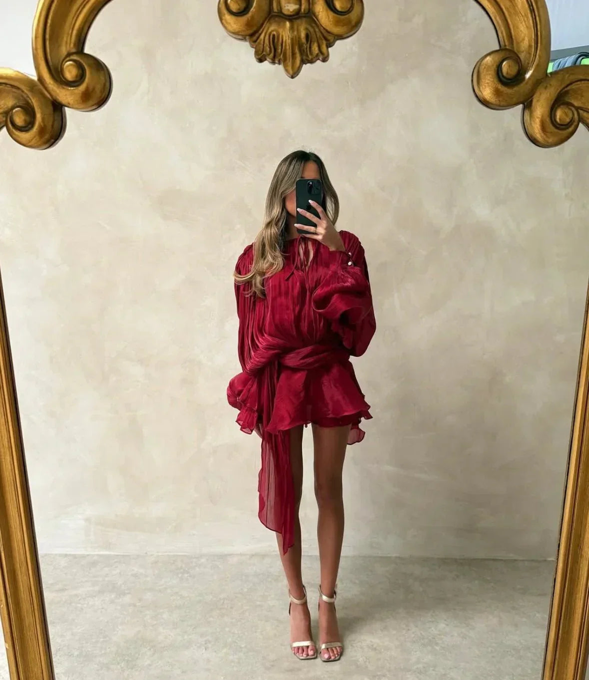 Person wearing a burgundy outfit in front of a decorative mirror.