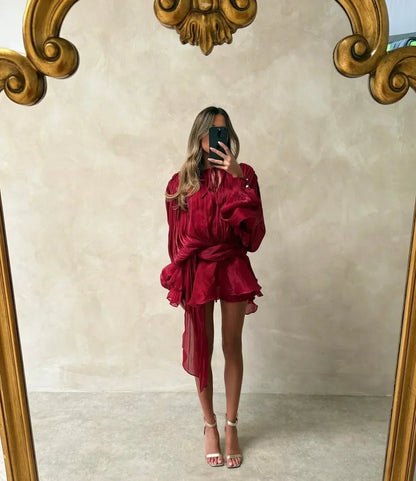 Person wearing a burgundy outfit in front of a decorative mirror.