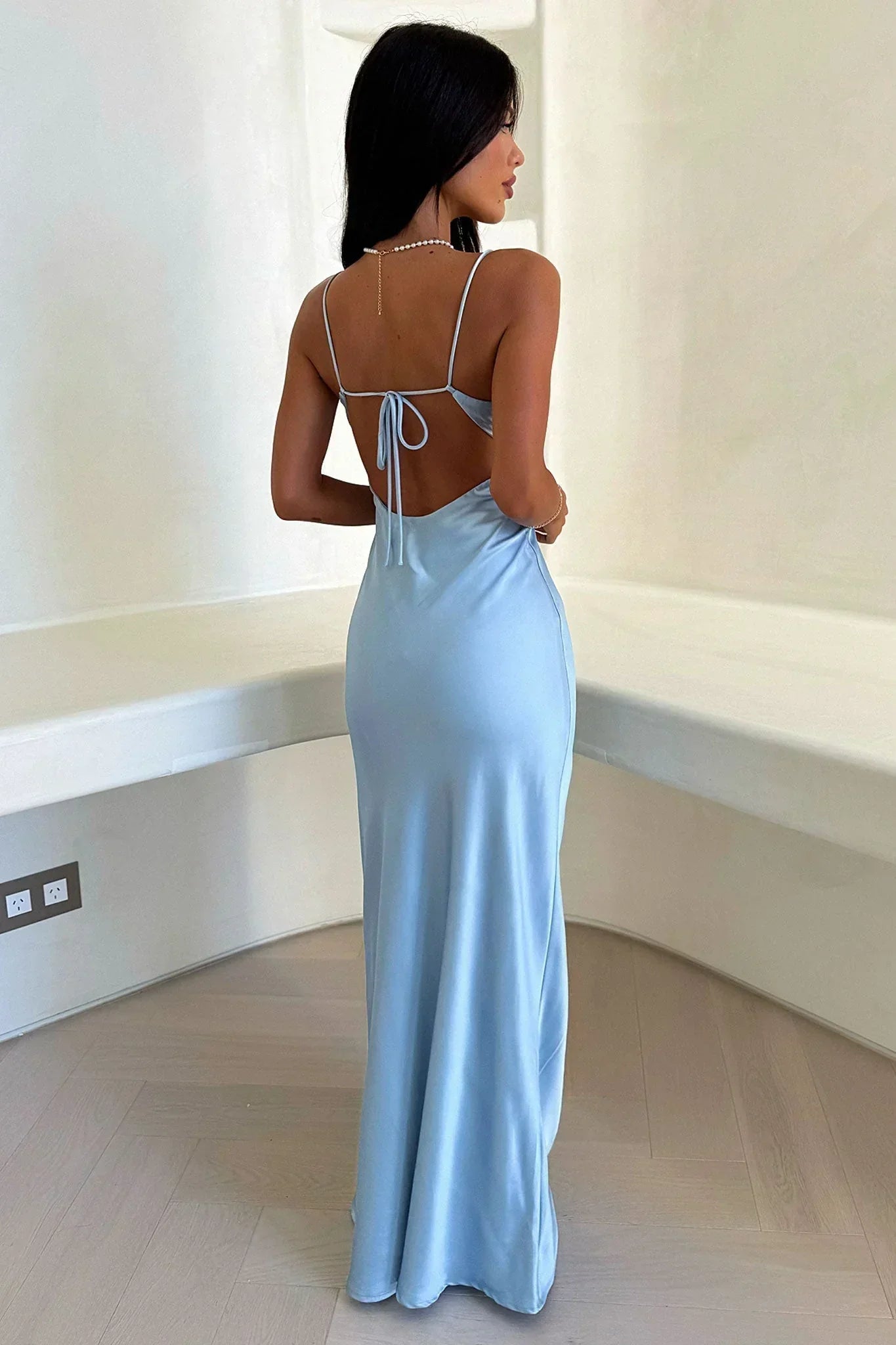 Woman wearing a light blue evening gown in a minimal indoor setting
