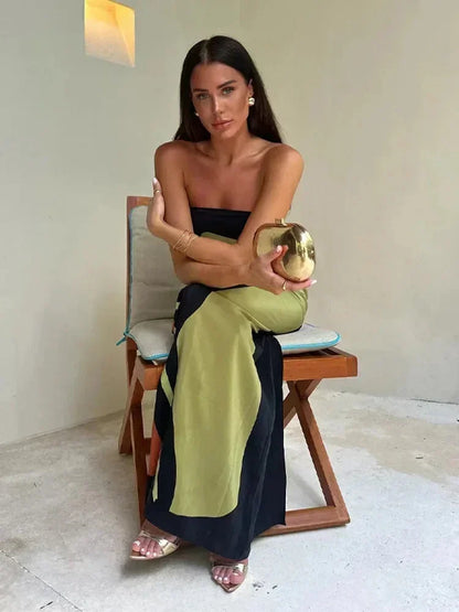 Woman sitting on a chair holding a gold apple in a minimalistic room.