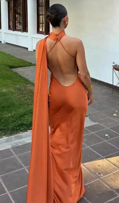 Person wearing an orange dress with a backless design, standing outdoors.