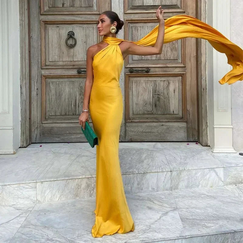 Woman in a yellow evening gown standing in front of a wooden door.