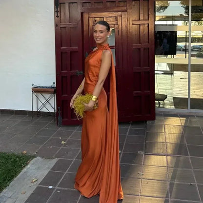 Woman in an orange dress holding a yellow clutch in front of a wooden door.