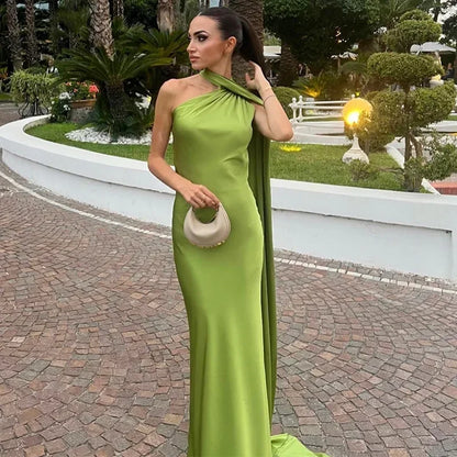 Woman in a green evening gown standing outdoors with a garden background