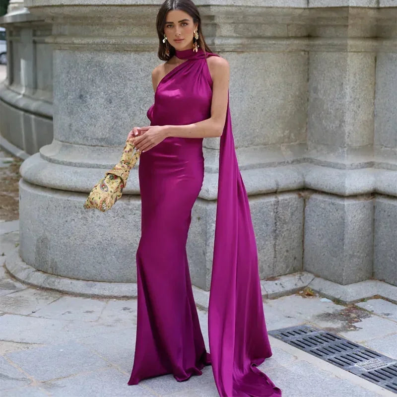 Woman in a magenta evening gown holding a gold clutch against a stone building background