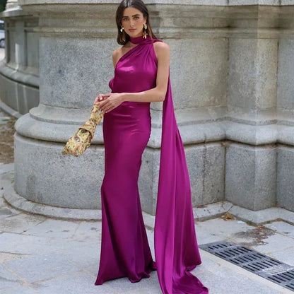Woman in a magenta evening gown holding a gold clutch against a stone building background