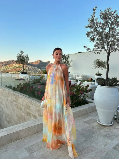 Woman in a colorful dress standing on a rooftop with scenic views and plants.