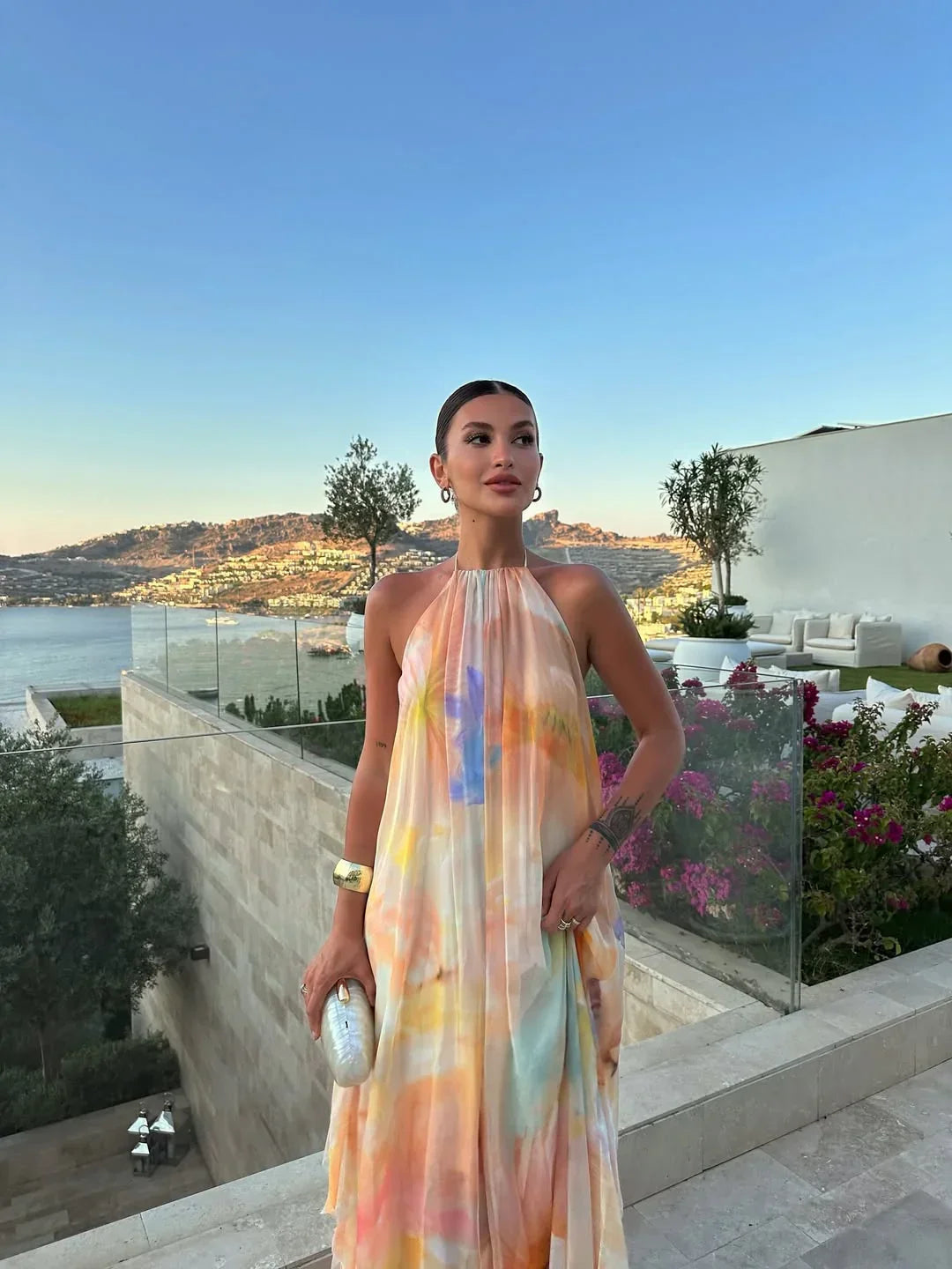 Woman in a colorful dress standing in an outdoor setting with a scenic view.