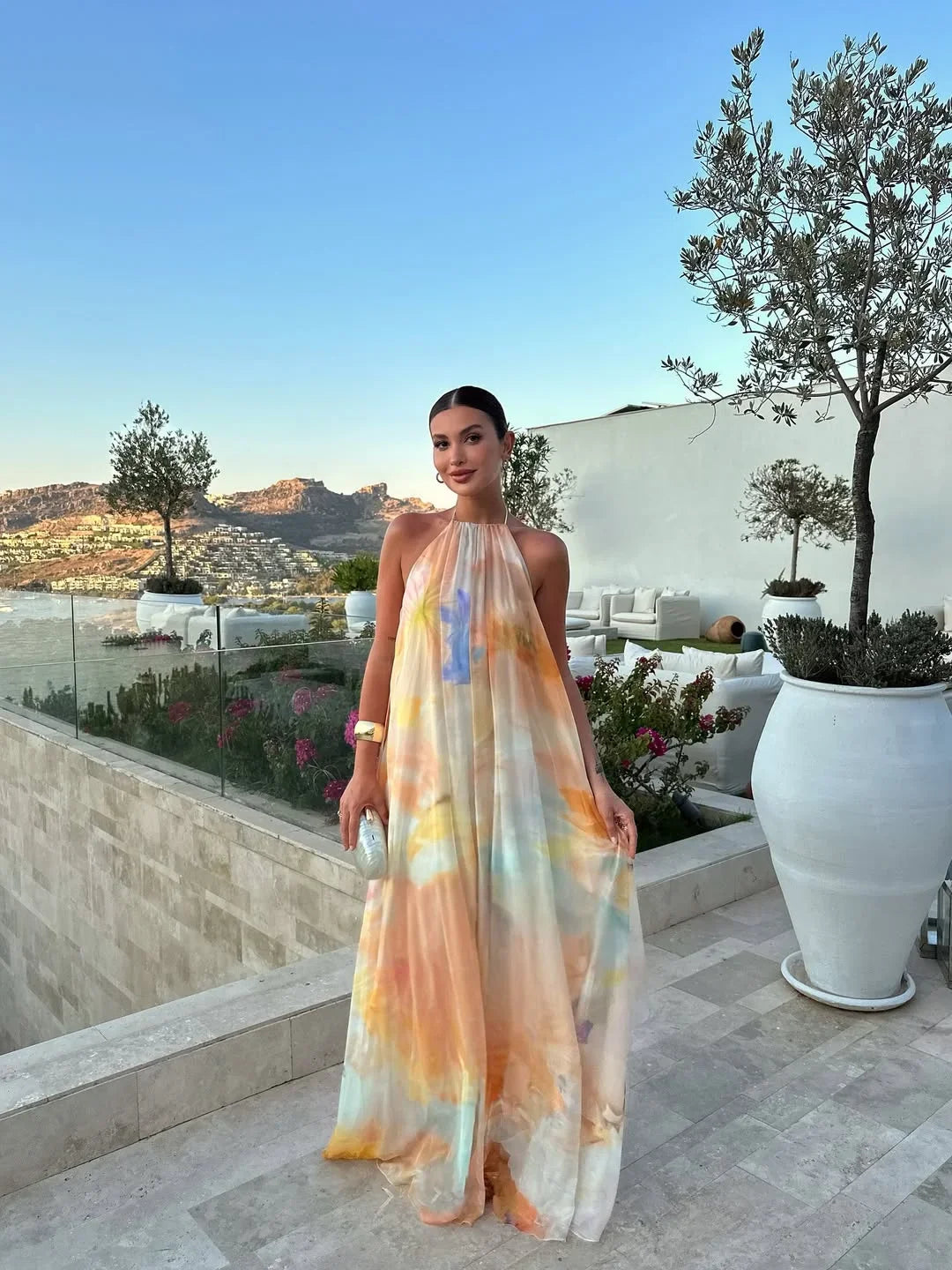 Woman in a colorful dress standing on a terrace with a scenic view
