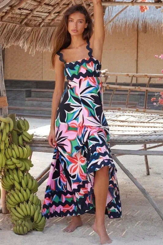 Woman in a colorful floral dress standing under a thatched roof with bananas in the background