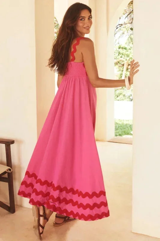 Woman wearing a pink dress with red accents in a bright room.