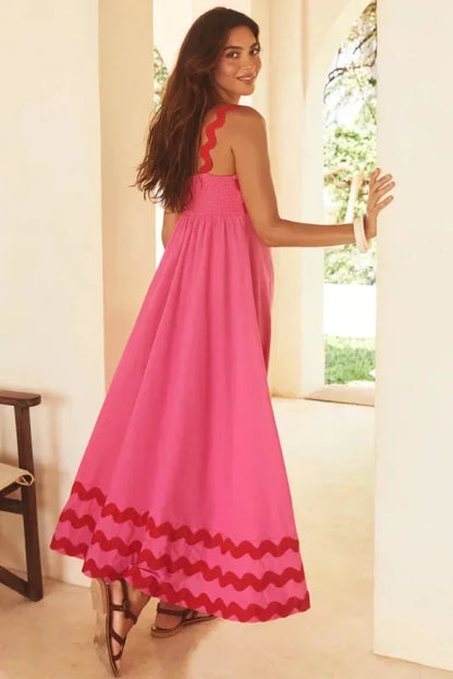 Woman wearing a pink dress with red accents in a bright room.