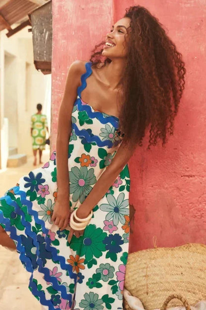 Woman wearing a floral dress against a pink wall.