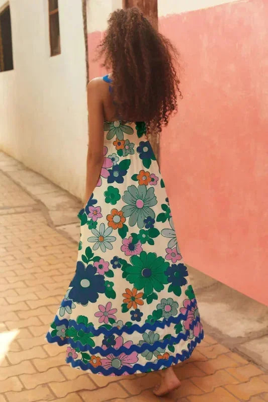 Woman wearing a floral dress walking on a street with a pink wall.