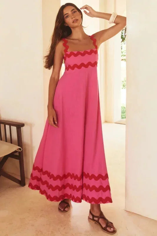 Woman wearing a pink dress with red accents in a bright room.