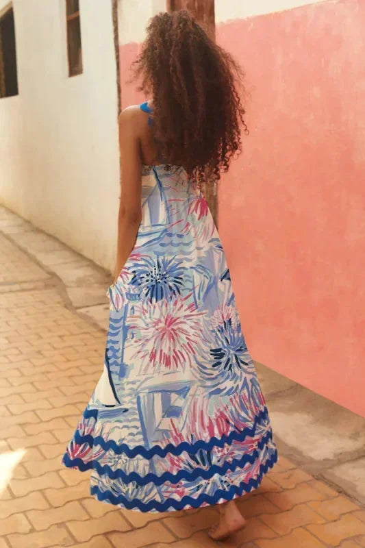 Woman wearing a colorful dress with floral patterns walking on a sidewalk.