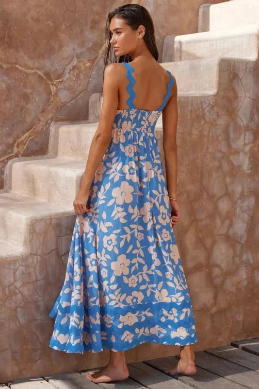 Woman in a blue floral dress standing on stone steps.