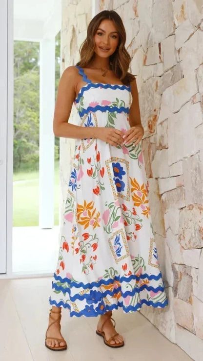 Woman wearing a colorful floral dress standing in front of a stone wall.