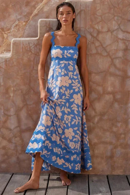 Woman wearing a blue floral dress standing against a stone wall.