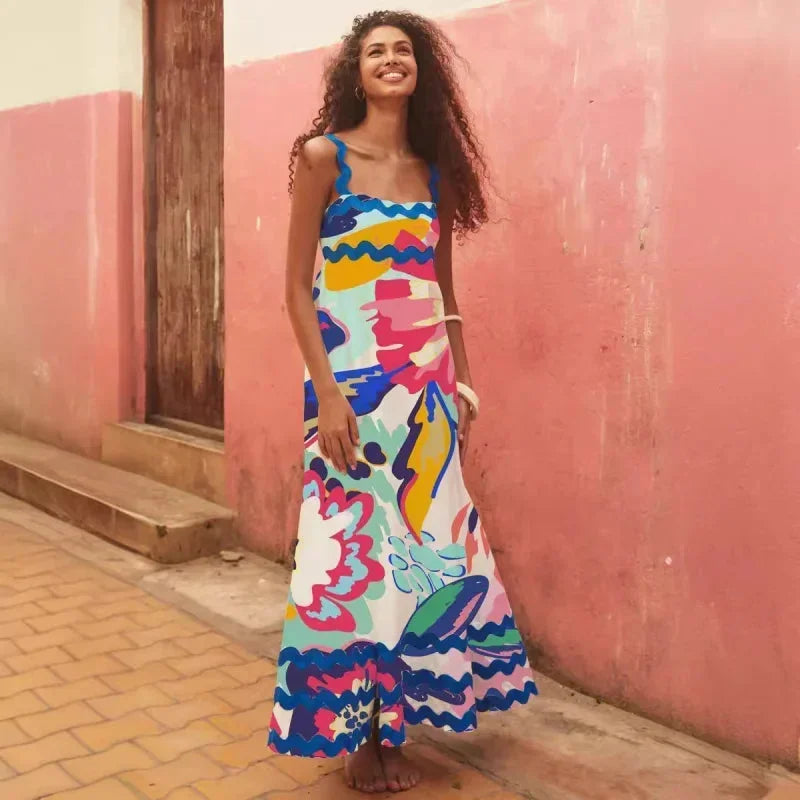 Woman wearing a colorful dress standing against a pink wall.