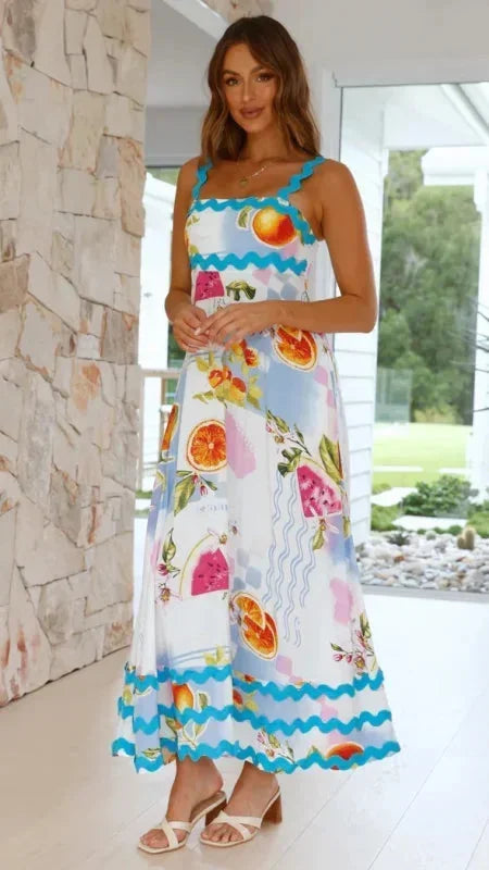 Woman wearing a colorful floral dress with a stone wall and garden view in the background