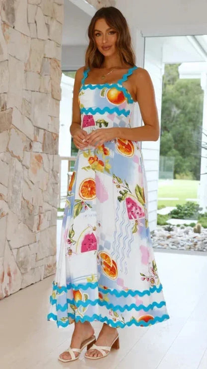 Woman wearing a colorful floral dress with a stone wall and garden view in the background