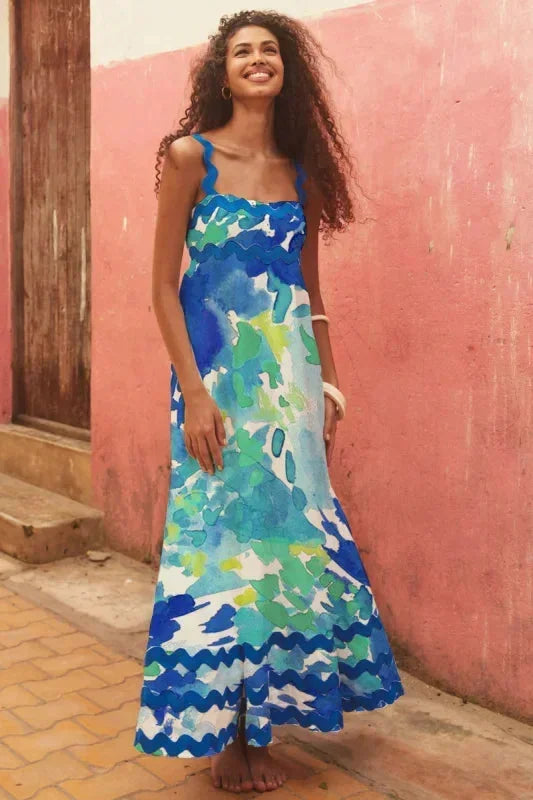 Woman wearing a colorful dress standing against a pink wall.