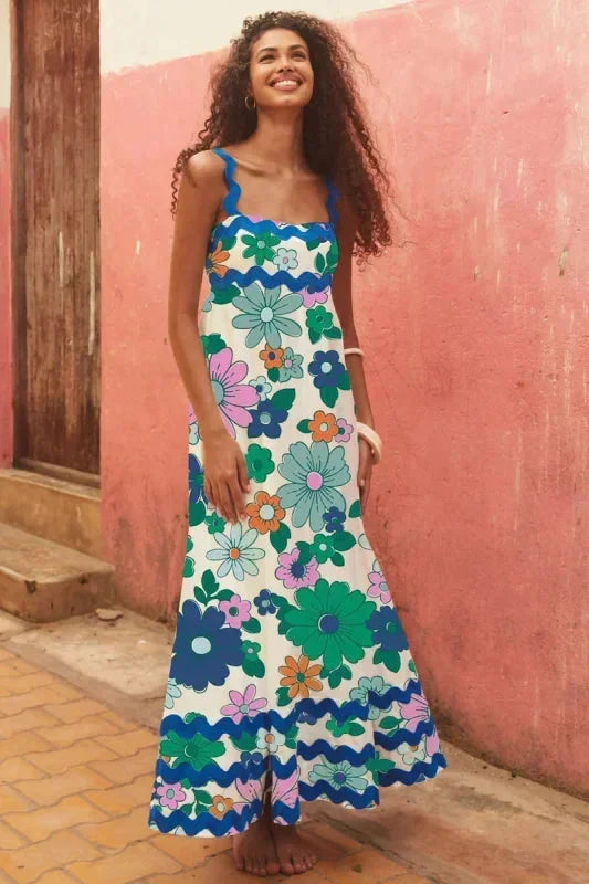 Woman wearing a colorful floral dress against a pink wall.