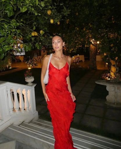 Woman in a red dress standing outdoors with trees and lanterns in the background