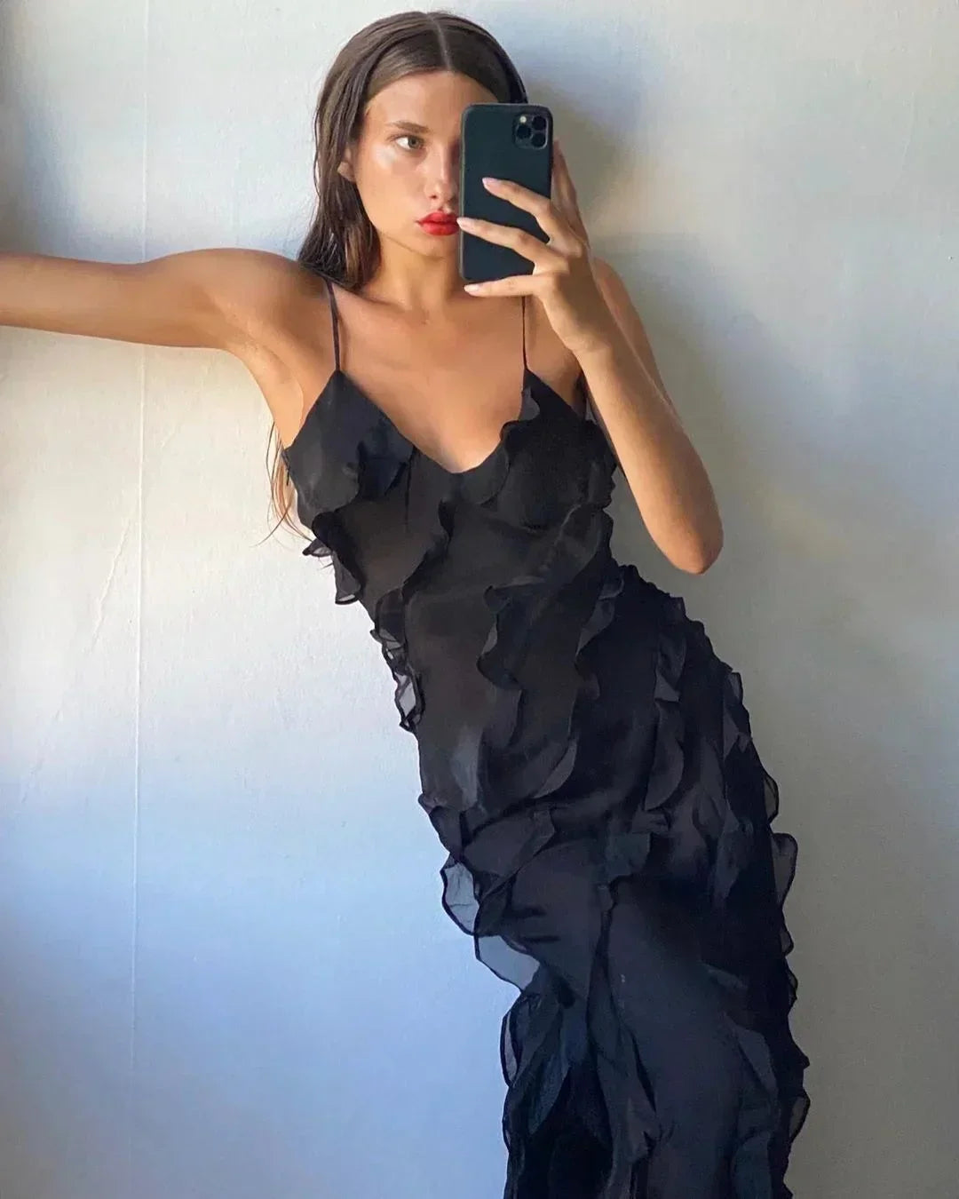 Woman wearing a black ruffled dress against a plain background