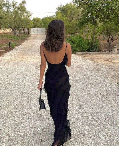 Woman in a black dress walking on a gravel path with trees in the background