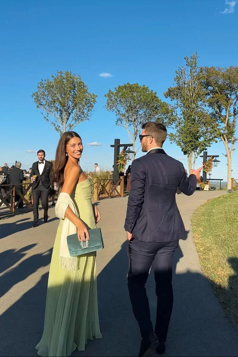 Man and woman in formal attire walking outdoors on a sunny day.
