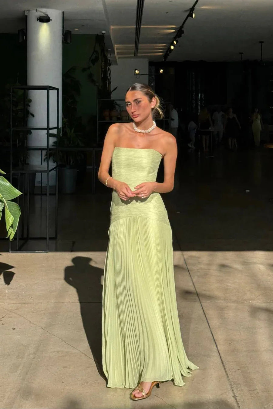 Woman in a light green strapless dress standing indoors.