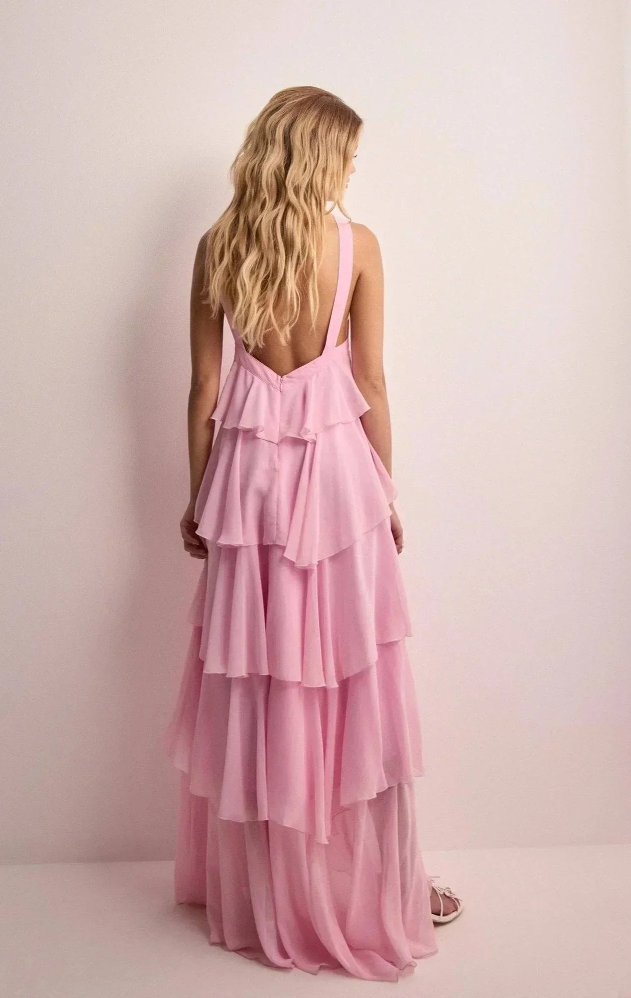 Woman wearing a pink layered dress against a plain background