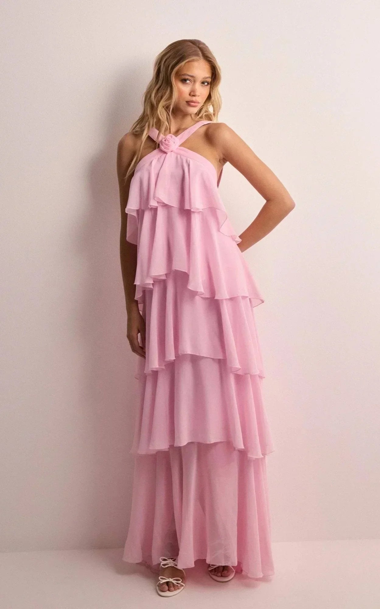 Woman wearing a pink ruffled dress against a plain background
