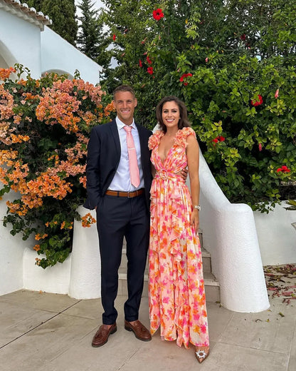 Man and woman standing together in a garden with flowers and greenery.