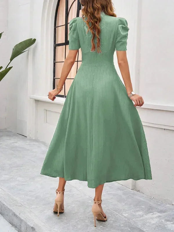 Woman wearing a green dress standing in front of a white wall.