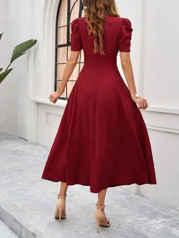 Woman wearing a burgundy dress with puff sleeves in an outdoor setting.