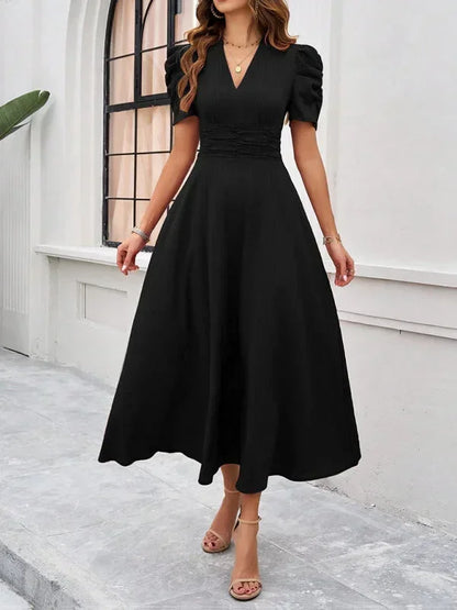 Woman wearing a black dress standing in front of a white building.