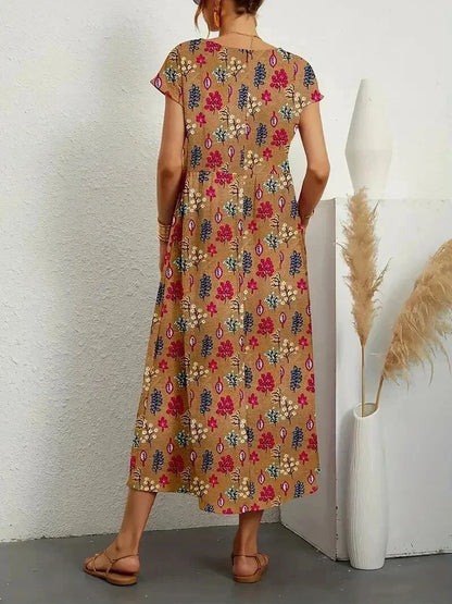 Woman wearing a floral dress standing against a white wall with decorative elements.