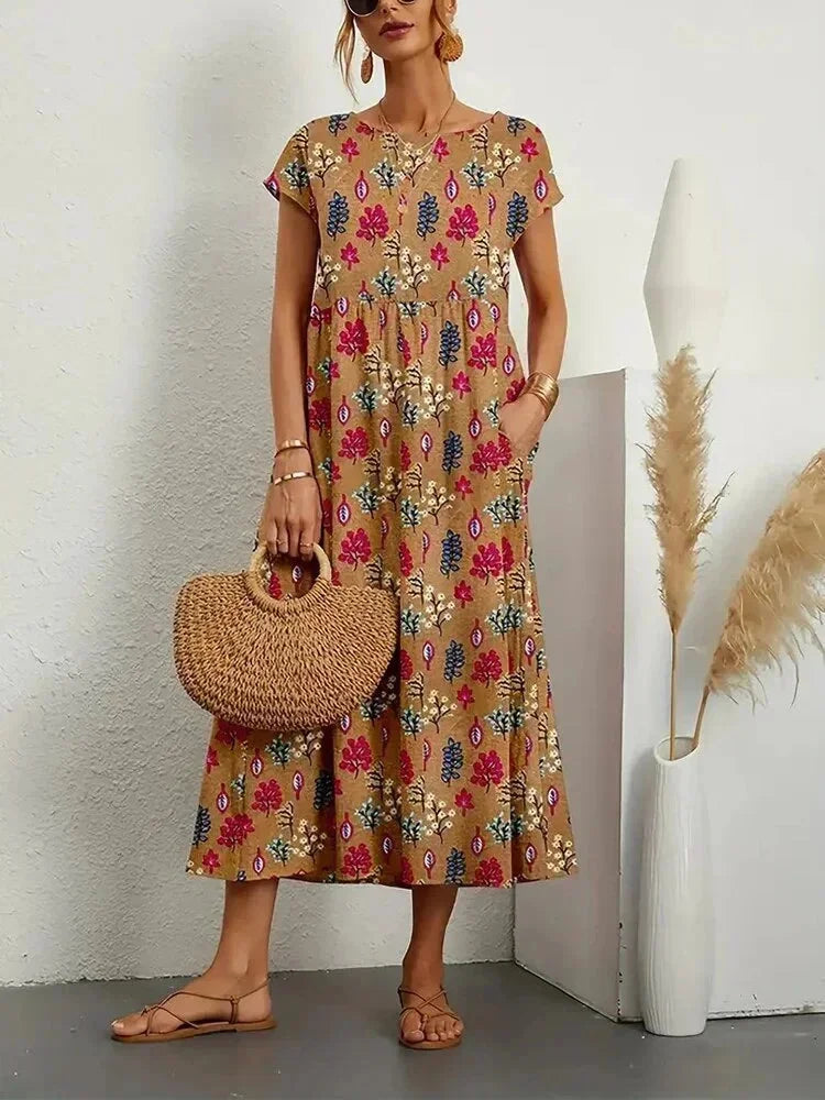 Woman wearing a floral dress holding a woven bag against a white wall.