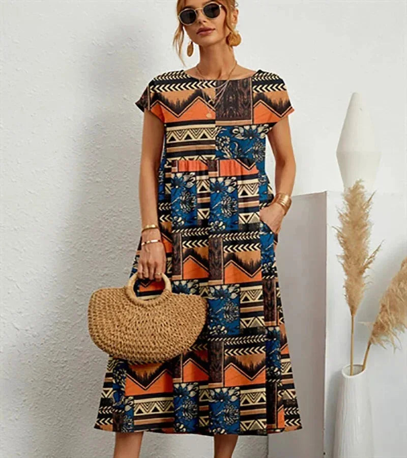 Woman wearing a patterned dress holding a straw bag against a white background