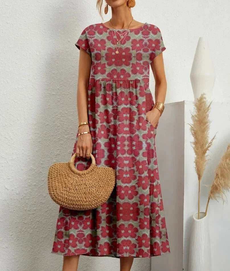 Woman wearing a red floral dress holding a woven bag against a white background