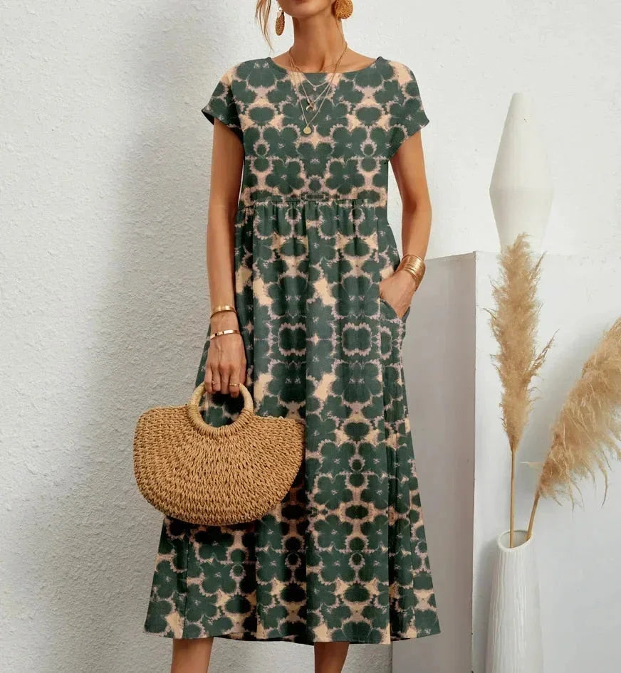 Woman wearing a green floral dress holding a woven bag against a white background