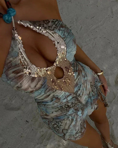 Close-up of a patterned bikini top with embellishments on a sandy background