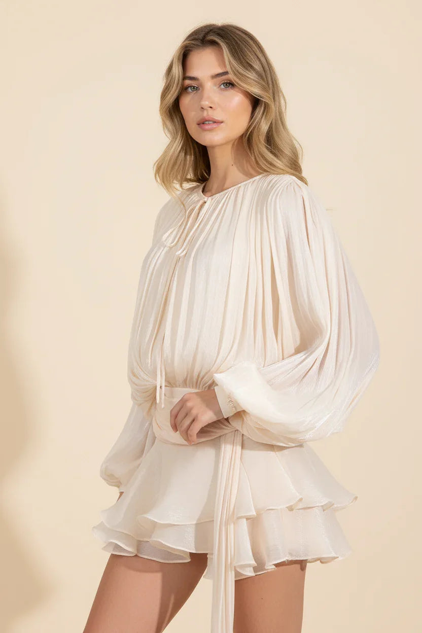 Woman wearing a cream-colored dress with long sleeves on a beige background