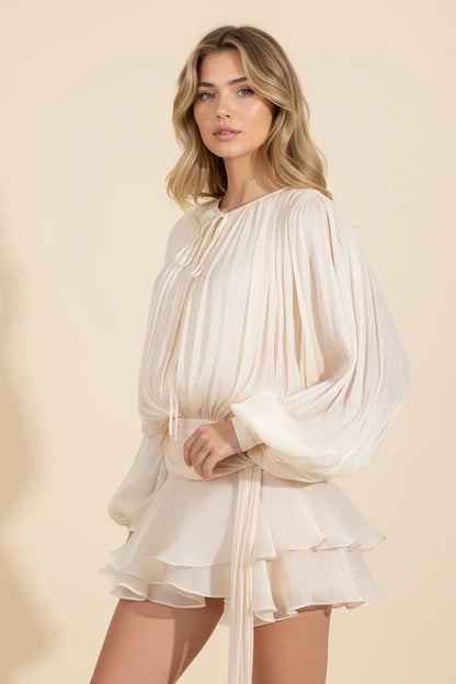 Woman wearing a cream-colored dress with long sleeves on a beige background