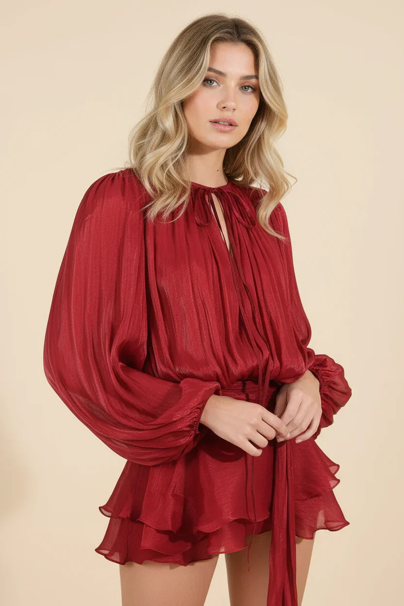 Woman wearing a red dress with long sleeves against a beige background