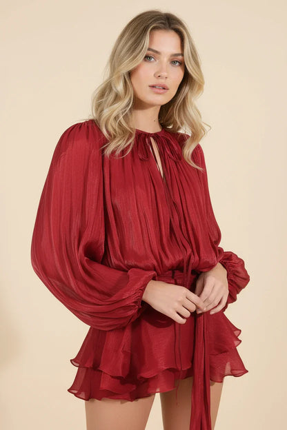 Woman wearing a red dress with long sleeves against a beige background